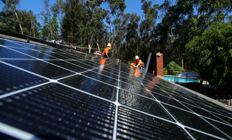 Solar installers from Baker Electric place solar panels on the roof of a residential home in Scripps Ranch, San Diego, California