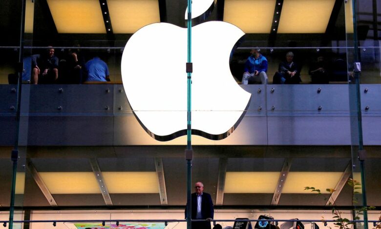 FILE PHOTO: A customer stands underneath an illuminated Apple logo as he looks out the window of the Apple store located in central Sydney