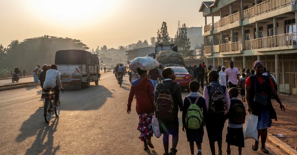School children walk along a street among pedestrians in Kigali