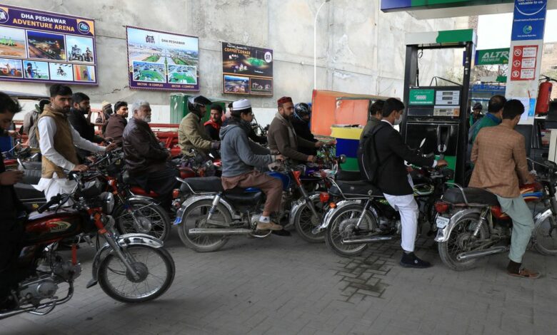 People wait for their turn to get fuel at a petrol station in Peshawar