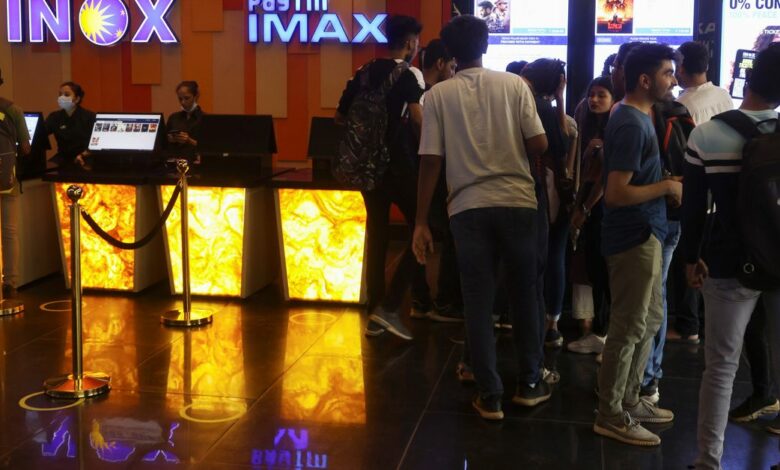 People wait to buy tickets outside an INOX movie theatre in Mumbai