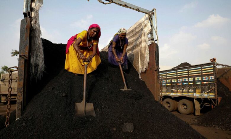 Workers unload coal from a supply truck at a yard on the outskirts of Ahmedabad