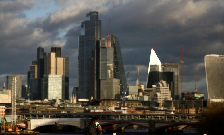 A  person walks across Waterloo Bridge with the City of London financial district in the background, in London