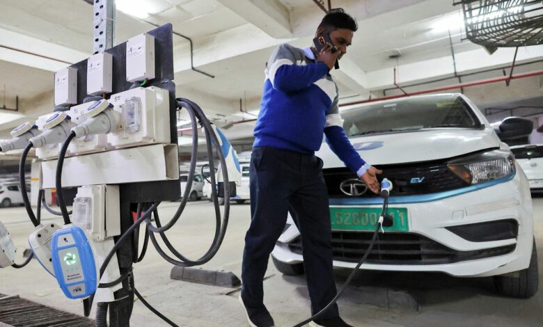 A man charges an electric vehicle (EV) at the charging hub of Indian ride-hailing BluSmart Electric Mobility in Gurugram