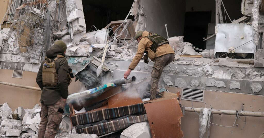 Ukrainian service men remove a grad rocket in a damaged house, in Kherson