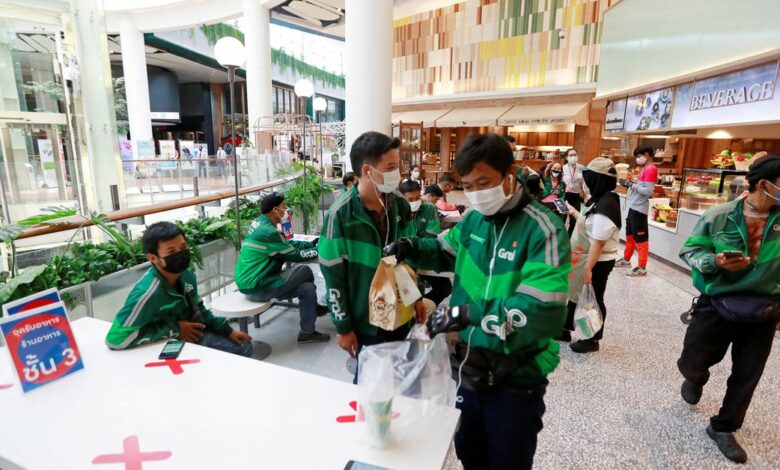 Staff of Grab, a food delivery service, wait for orders inside Central World mall in Bangkok