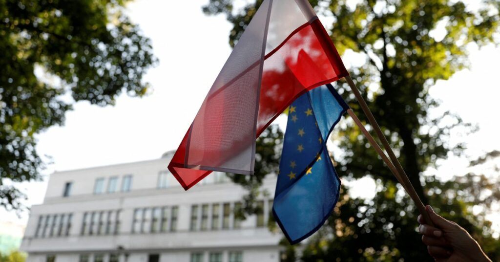 A protester holds EU and Polish flags during an anti-government protest in support of free courts in front of the the Senate building in Warsaw