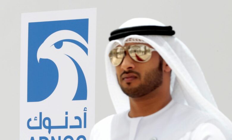 An Emirati man is seen near the logo of  ADNOC in Ruwais