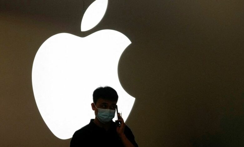 A man talks on a phone in front of an Apple logo outside its store in Shanghai