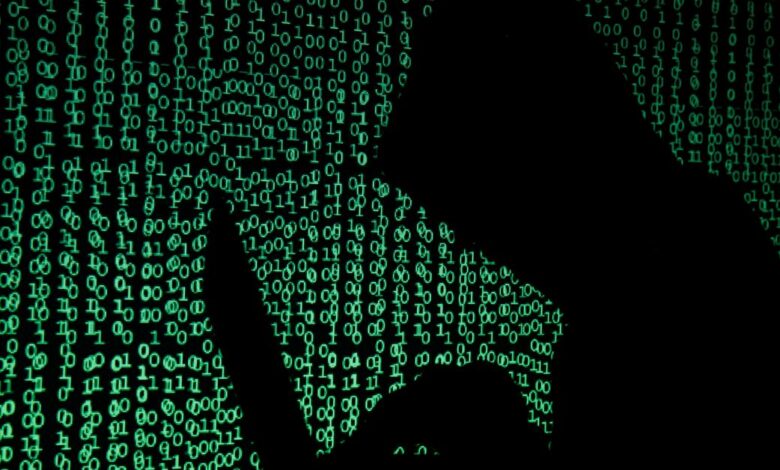 Hooded man holds laptop computer as cyber code is projected on him in this illustration picture