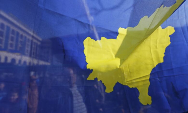 People are pictured through Kosovo flag as they take part in celebrations of the 10th anniversary of Kosovo