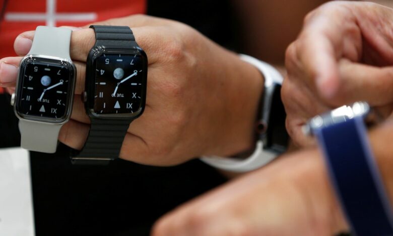An attendee holds two titanium Apple Watch Edition smart watches in the demonstration area during a launch event at their headquarters in Cupertino