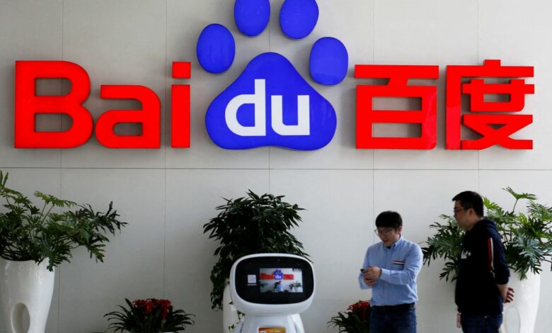 Men interact with a Baidu AI robot near the company logo at its headquarters in Beijing