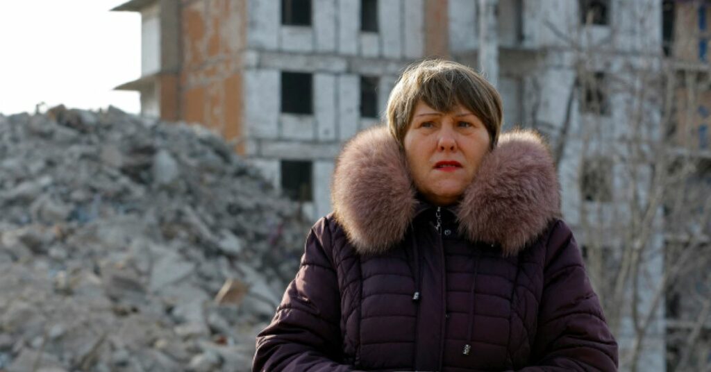 Tatiana Bushlanova stands next to the ruins of her apartment block, demolished due to heavy damage, in Mariupol