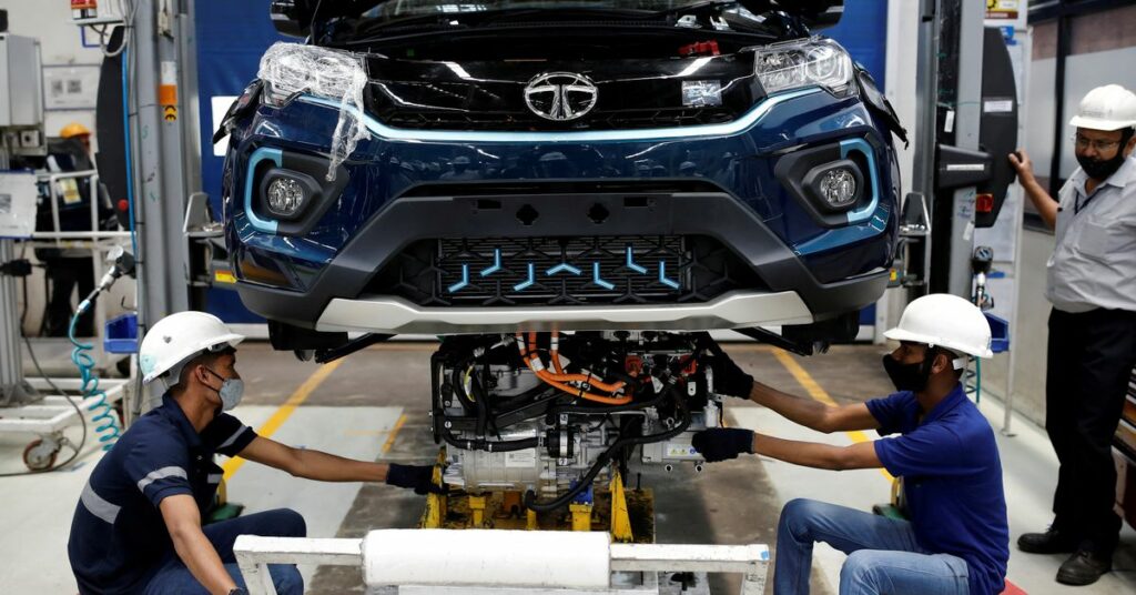 Workers install the electric motor inside a Tata Nexon electric sport utility vehicle (SUV) at the Tata Motors plant in Pune