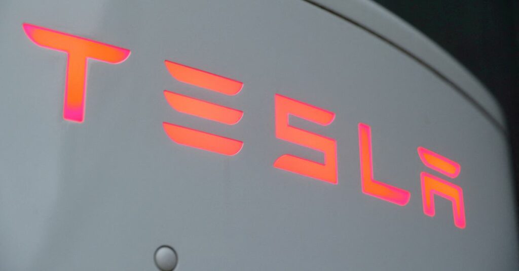 The logo of Tesla is seen at a Tesla Supercharger station