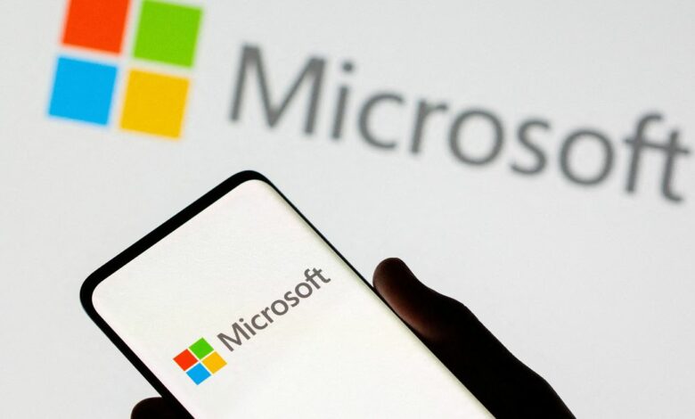 Smartphone is seen in front of Microsoft logo displayed in this illustration taken