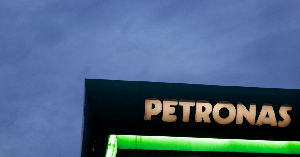 A logo of a Petronas fuel station is seen against a darkening sky in Kuala Lumpur