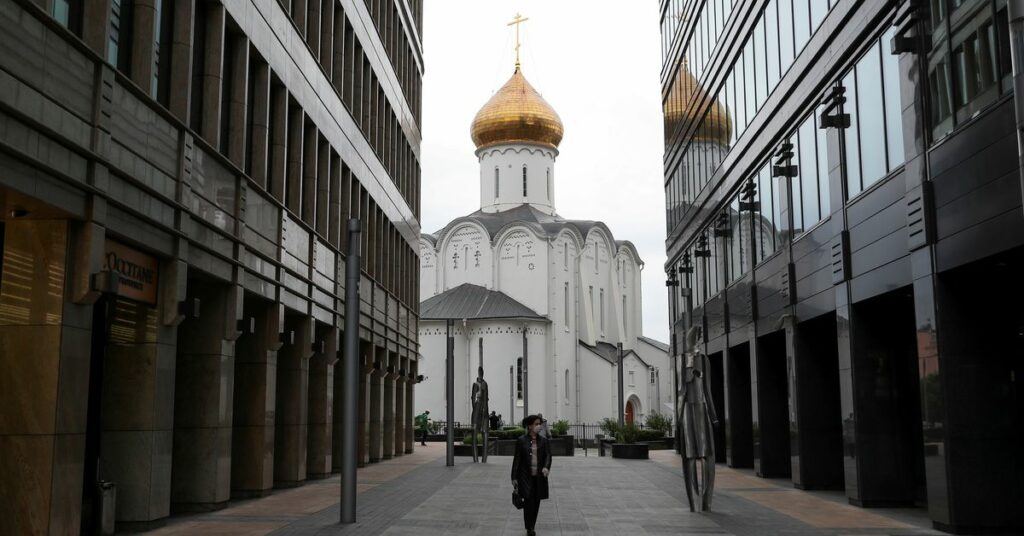 A woman wearing a protective face mask walks walks in a business district in Moscow
