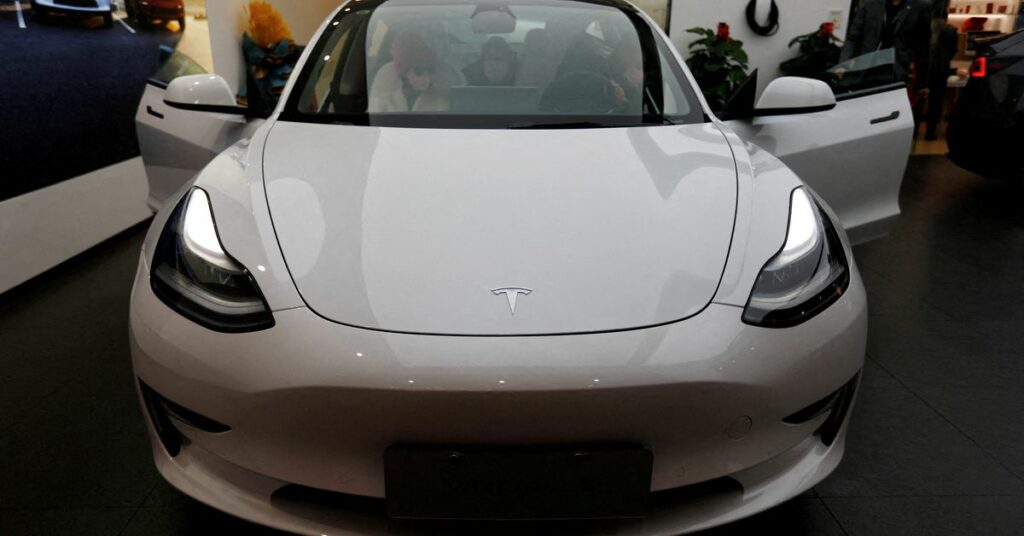 Visitors check a Tesla Model 3 car at a showroom of the U.S. electric vehicle maker in Beijing, China