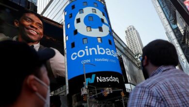 People watch as the logo for Coinbase Global Inc, the biggest U.S. cryptocurrency exchange, is displayed on the Nasdaq MarketSite jumbotron at Times Square in New York