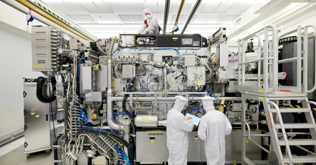 Employees are seen working on the final assembly of ASML's TWINSCAN NXE:3400B semiconductor lithography tool with its panels removed, in Veldhoven