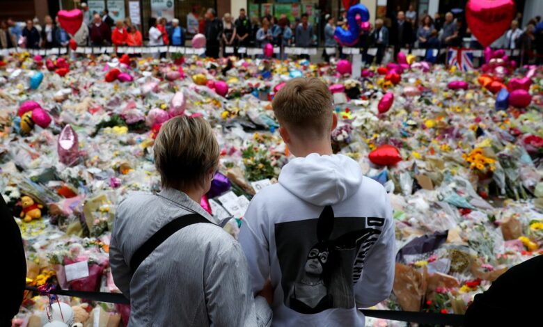 A boy wearing an Ariana Grande hoodie looks at flowers and tributes left for the victims of the attack on Manchester Arena in St Ann's Square in Manchester