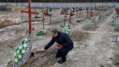 People visit graves of unidentified people, in a day of the first anniversary of Russia's attack on Ukraine, in Bucha
