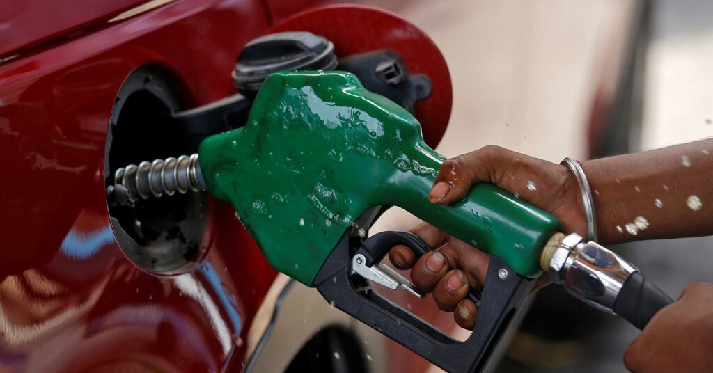 A worker holds a nozzle to pump petrol into a vehicle at a fuel station in Mumbai