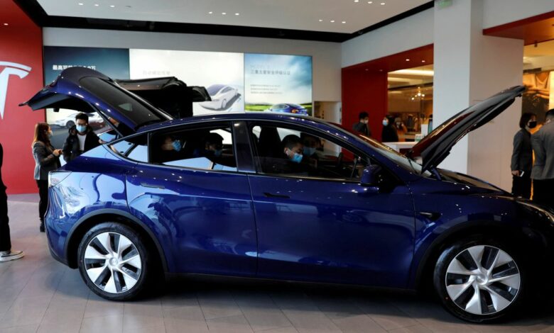 FILE PHOTO: Visitors wearing face masks check a China-made Tesla Model Y sport utility vehicle (SUV) at the electric vehicle maker
