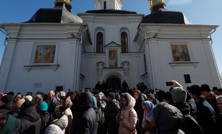 Believers pray while they block an entrance to a church at a compound of the Kyiv Pechersk Lavra monastery in Kyiv