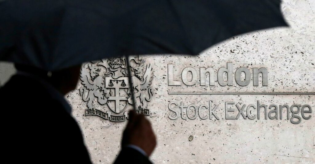 FILE PHOTO: A man shelters under an umbrella as he walks past the London Stock Exchange