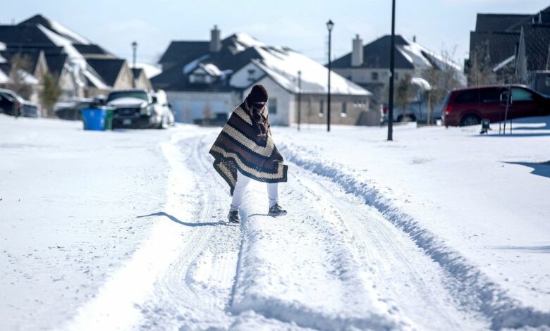 A man walks to his friend's home in a neighborhood without electricity in Pflugerville, Texas
