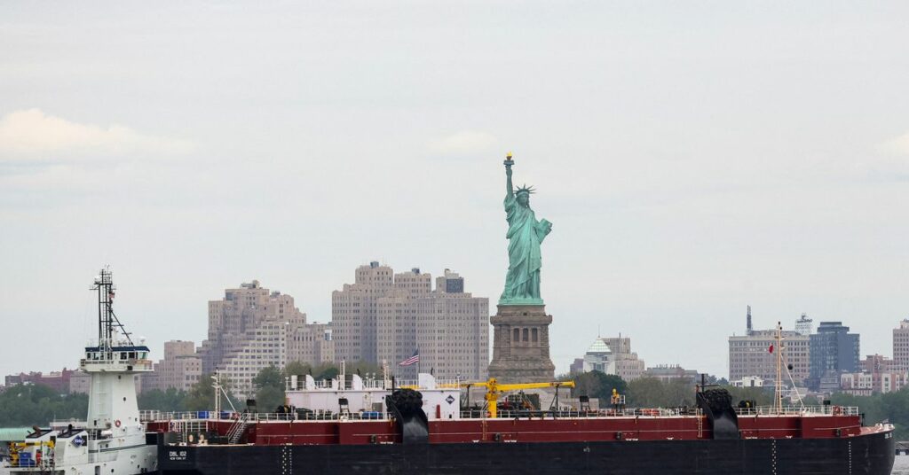 A tug boat pushes an oil barge through New York Harbor