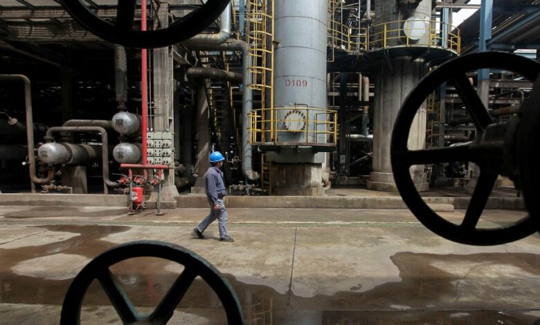 A worker walks past oil pipes at a refinery in Wuhan, Hubei province
