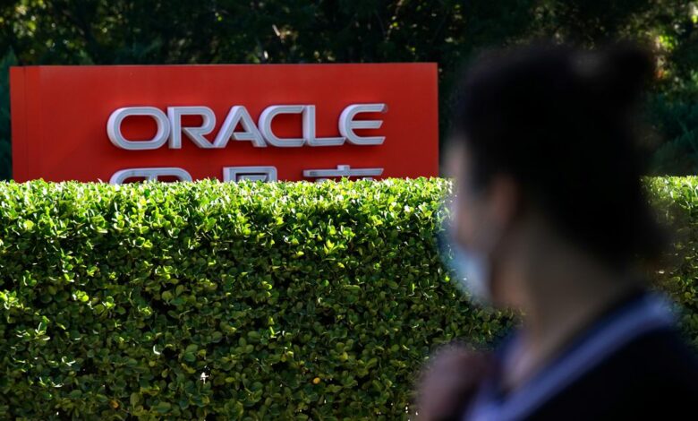 Pedestrian wearing face mask following the COVID-19 outbreak walks past a sign of Oracle in front of its office buildings in Beijing