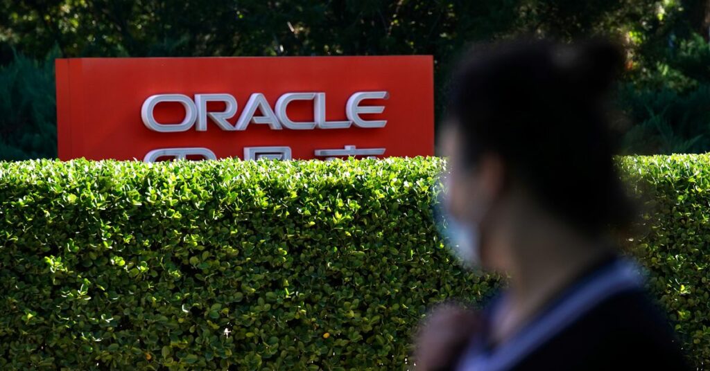 Pedestrian wearing face mask following the COVID-19 outbreak walks past a sign of Oracle in front of its office buildings in Beijing