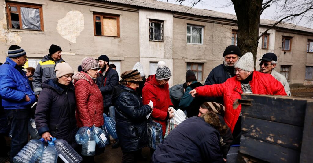 Residents queue to receive food and water brought in by Ukraine's State Emergency Service members, in Chasiv Yar