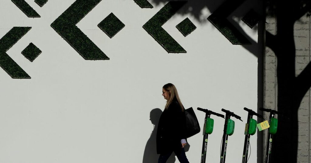 A woman walks past electric Lime scooters parked on the sidewalk in downtown Los Angeles, California