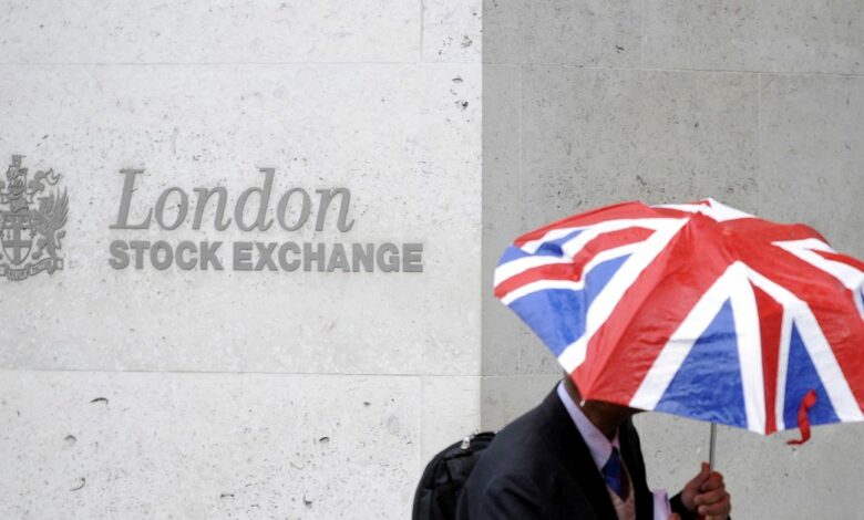 A worker shelters from the rain as he passes the London Stock Exchange in London