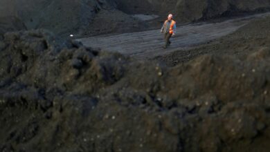 Worker walks past coal piles at a coal coking plant in Yuncheng