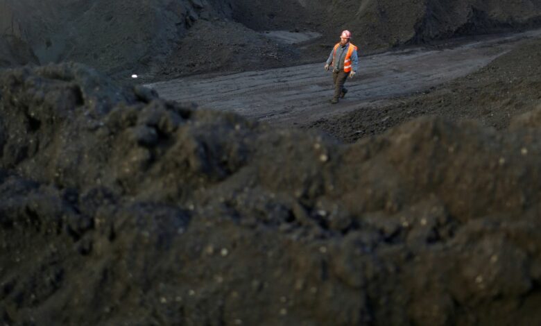 Worker walks past coal piles at a coal coking plant in Yuncheng
