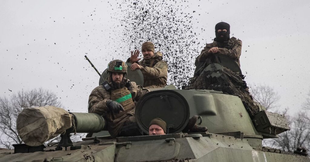 Ukrainian service members ride a self-propelled howitzer near Bakhmut