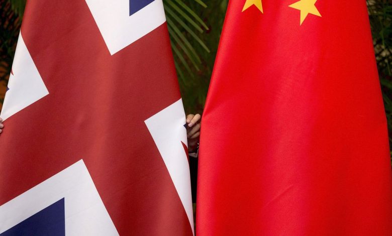 A worker adjusts British and China national flags on display for a signing ceremony at the seventh UK-China Economic and Financial Dialogue
