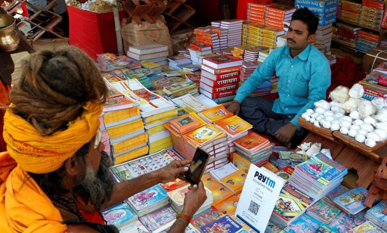 A Sadhu or a Hindu holy man pays the vendor through Paytm, a digital wallet company, after buying a book during the annual religious festival of Magh Mela in Allahabad