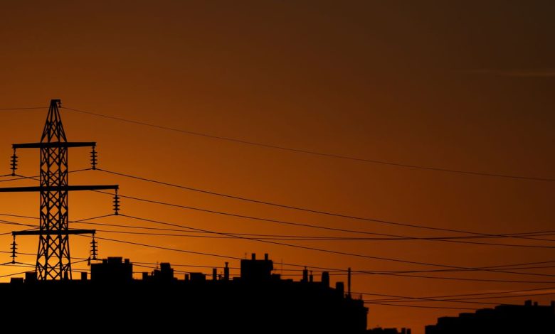High-voltage power lines and an electricity pylon are pictured at dusk outside Madrid