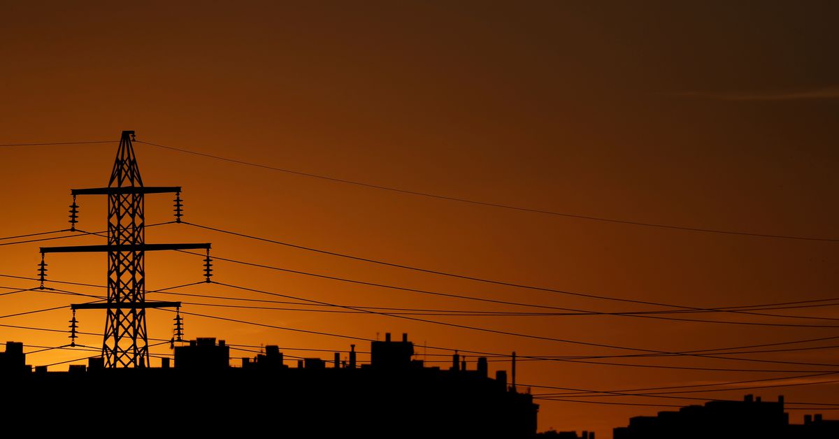 High-voltage power lines and an electricity pylon are pictured at dusk outside Madrid