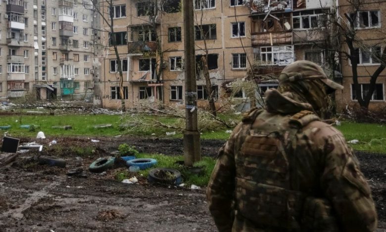 A Ukrainian service member walks near residential buildings damaged by a Russian military strike in the front line town of Bakhmut
