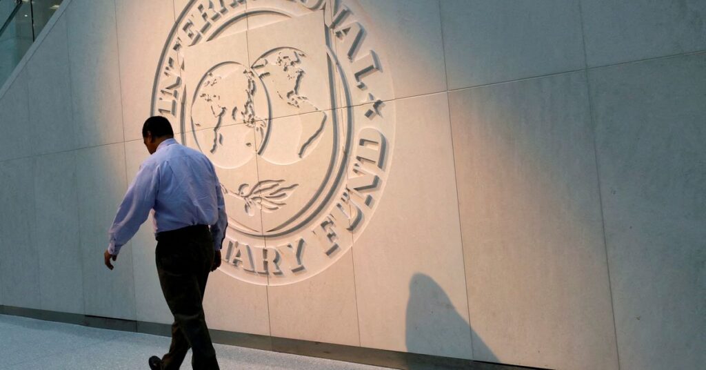 Man walks past the IMF logo at HQ in Washington