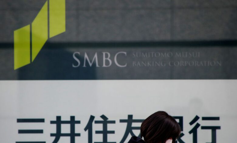 Woman walks past a sign board of Sumitomo Mitsui Banking Corporation, part of SMFG outside its branch in Tokyo
